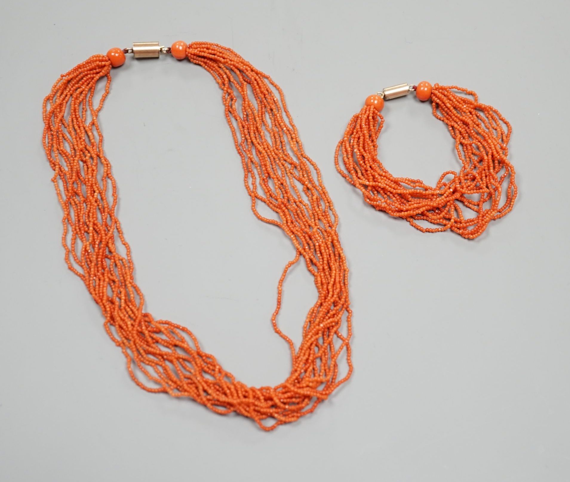 A multi strand coral bead necklace, 39cm and matching bracelet, 15.5cm, both with yellow metal barrel shaped clasps.